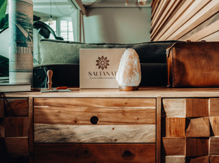 In view: A beautiful and unique, hand-crafted Salt Lamp placed on an elegant wooden table in an indoor setting 